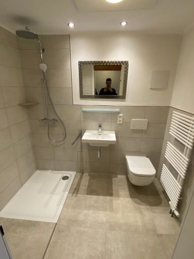 Modernes Badezimmer mit Dusche, Waschbecken und WC, hell und gut ausgestattet.