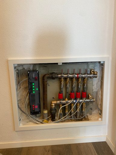 Installationsbox mit Heizkreisverteilung und Steuerelementen an der Wand.