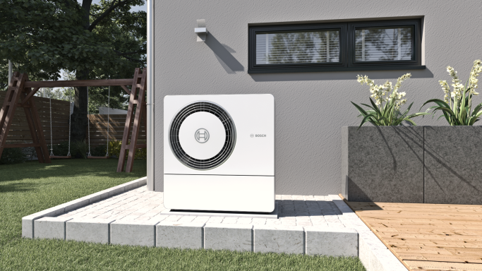 Außeneinheit einer Wärmepumpe neben einem Neubau